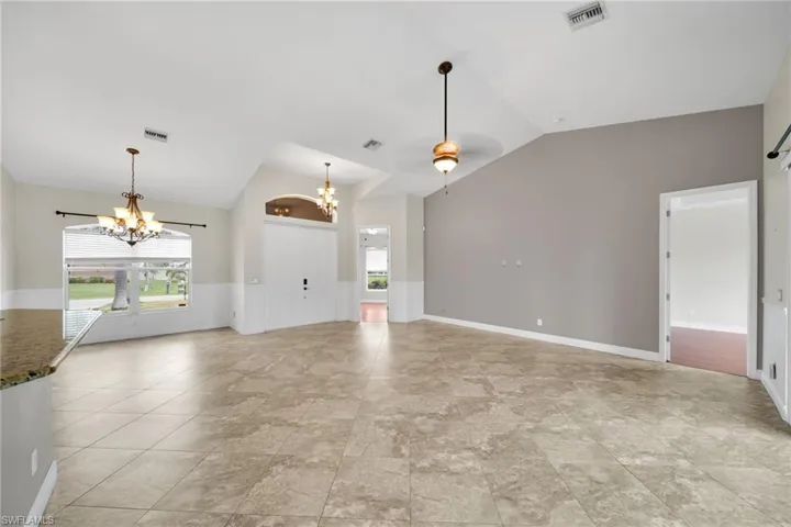 Unfurnished living room with a chandelier and lofted ceiling