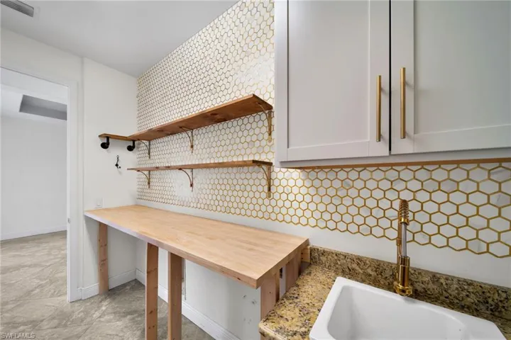 Kitchen view of a sink, baseboards, and open shelves