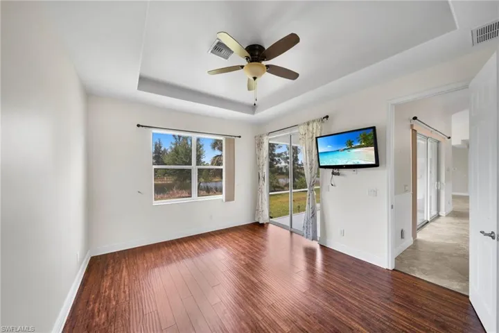 Spare room with a tray ceiling, ceiling fan, wood finished floors, and baseboards