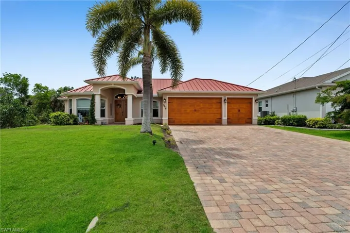 View of front facade with a standing seam roof, decorative driveway, a garage, and a front yard