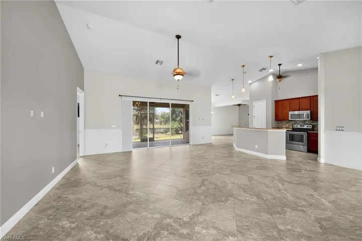 Unfurnished living room with high vaulted ceiling, baseboards, and a ceiling fan