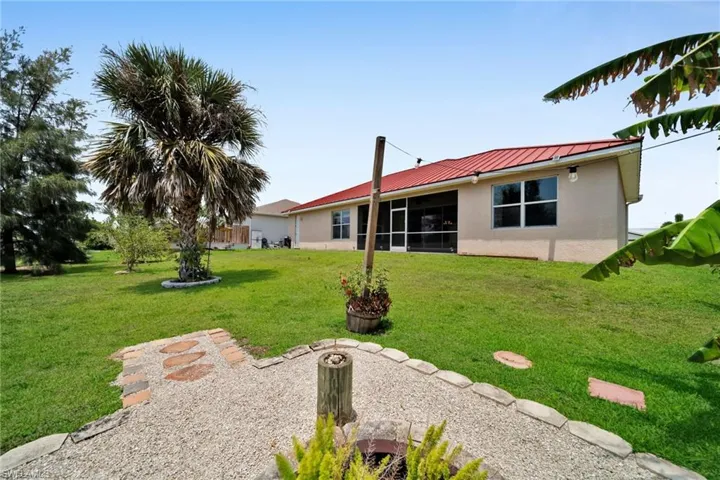 Back of property with stucco siding, metal roof, a yard, a standing seam roof, and a sunroom