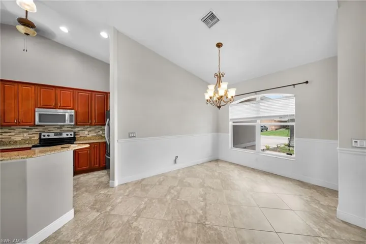 Kitchen with stainless steel appliances, tasteful backsplash, a chandelier, pendant lighting, and light stone counters