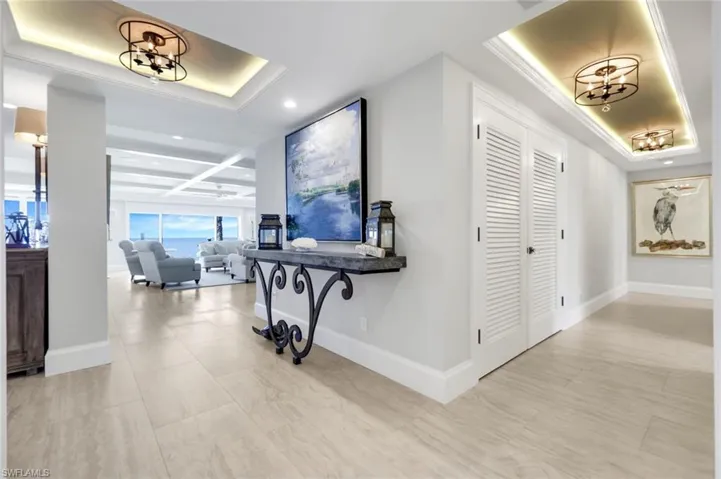 Corridor featuring a chandelier, a raised ceiling, and recessed lighting