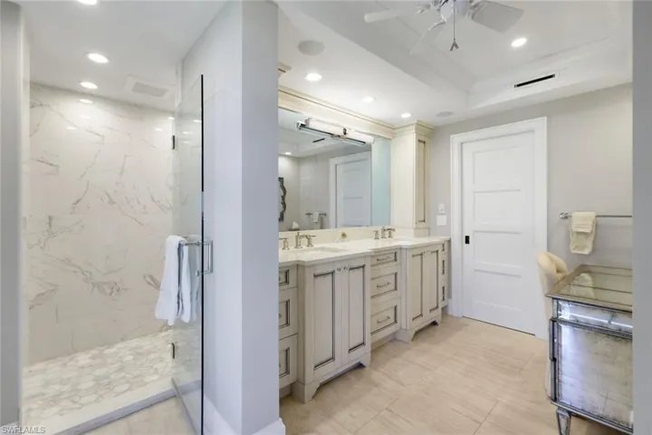 Bathroom with a marble finish shower, double vanity, recessed lighting, and ceiling fan