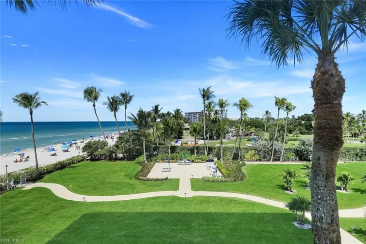 Surrounding community with view of water and beach and a yard