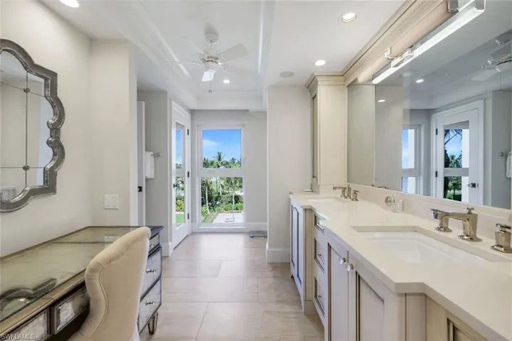 Bathroom featuring a ceiling fan, plenty of natural light, double vanity, recessed lighting, and light tile patterned floors