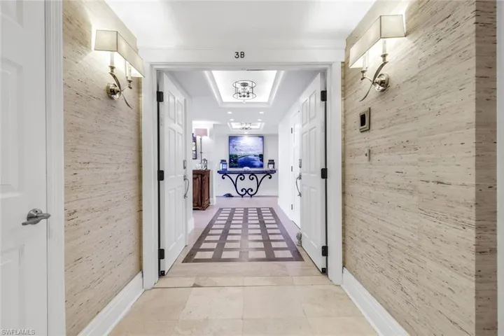 Hall featuring light tile patterned flooring and a raised ceiling