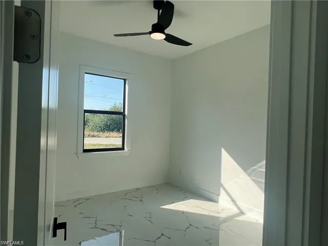 Empty room with marble look tiles and ceiling fan