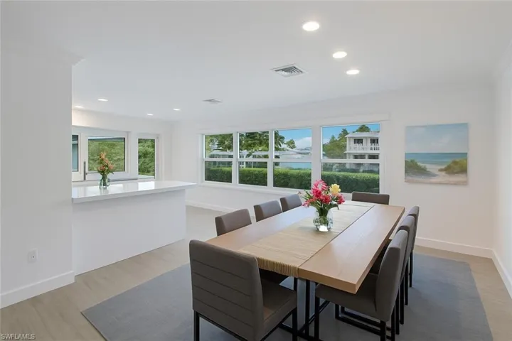 Dining area featuring ornamental molding, healthy amount of natural light, light wood-style floors, a water view, and recessed lighting