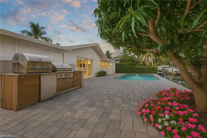 View of pool with a patio, exterior kitchen, and a water view