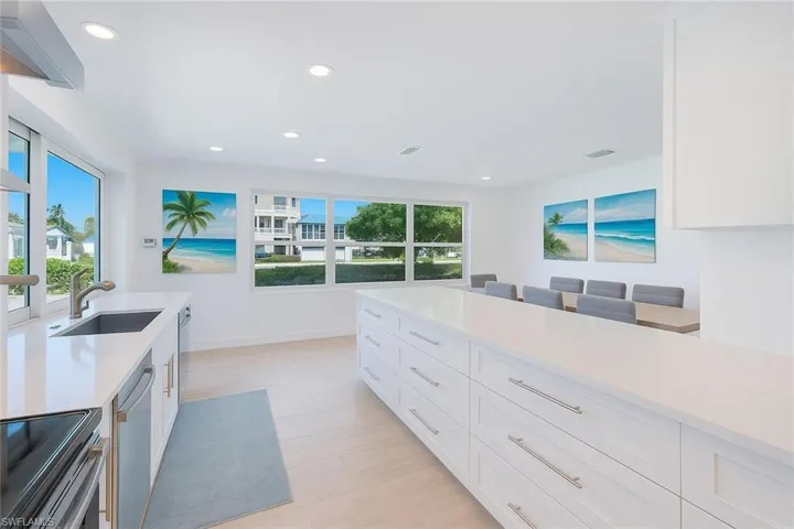 Kitchen with white cabinets, appliances with stainless steel finishes, a kitchen breakfast bar, recessed lighting, and light stone countertops