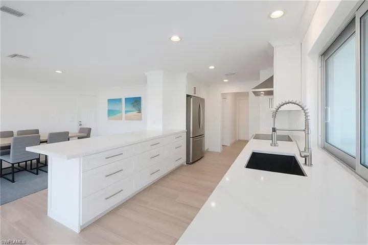 Kitchen featuring a peninsula, white cabinetry, recessed lighting, light stone countertops, and light wood-type flooring
