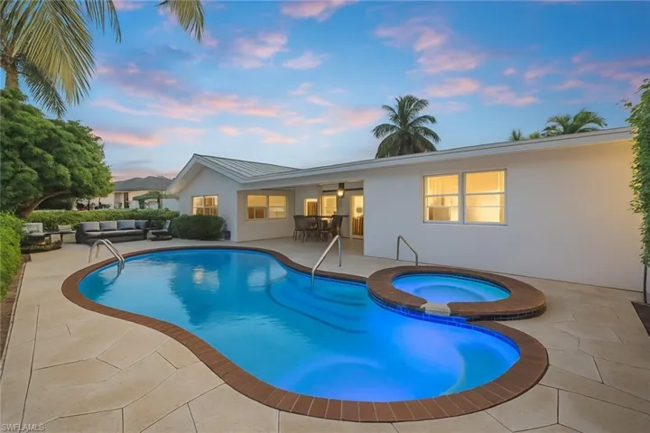 Pool at dusk featuring a patio, an outdoor living space, a pool with connected hot tub, and a ceiling fan