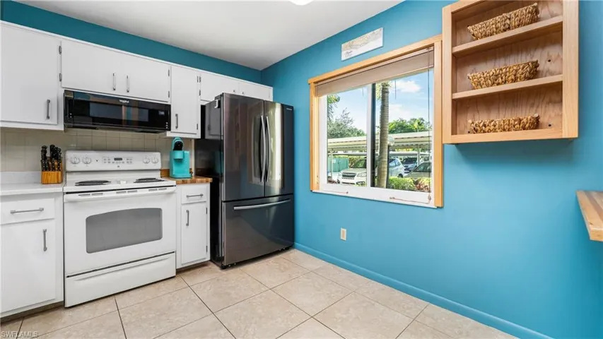 Kitchen with electric stove, freestanding refrigerator.