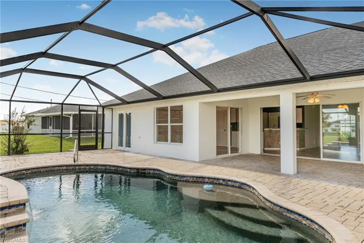 View of swimming pool with a patio, ceiling fan, and glass enclosure