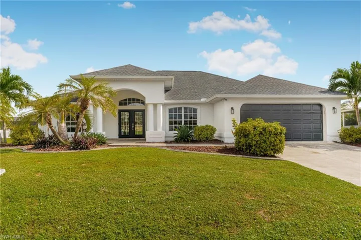 View of front of home with french doors, a front lawn, and a garage