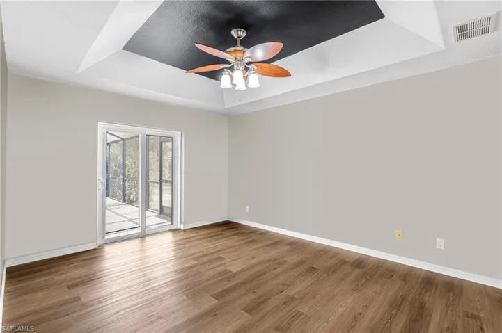 Spare room featuring a textured ceiling, hardwood / wood-style floors, ceiling fan, and a raised ceiling