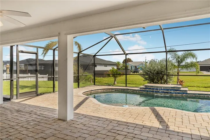 View of swimming pool with a hot tub, glass enclosure, a patio, ceiling fan, and a yard