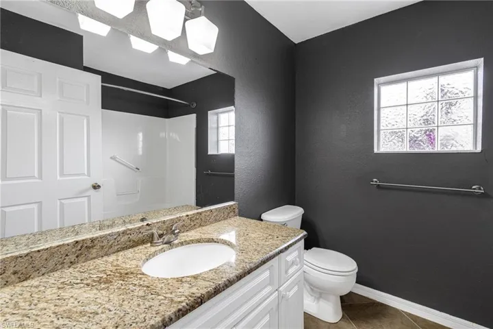 Bathroom featuring vanity, tile patterned flooring, a healthy amount of sunlight, and toilet