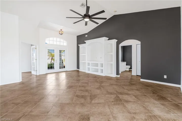 Unfurnished living room with french doors, high vaulted ceiling, ceiling fan, and tile patterned floors