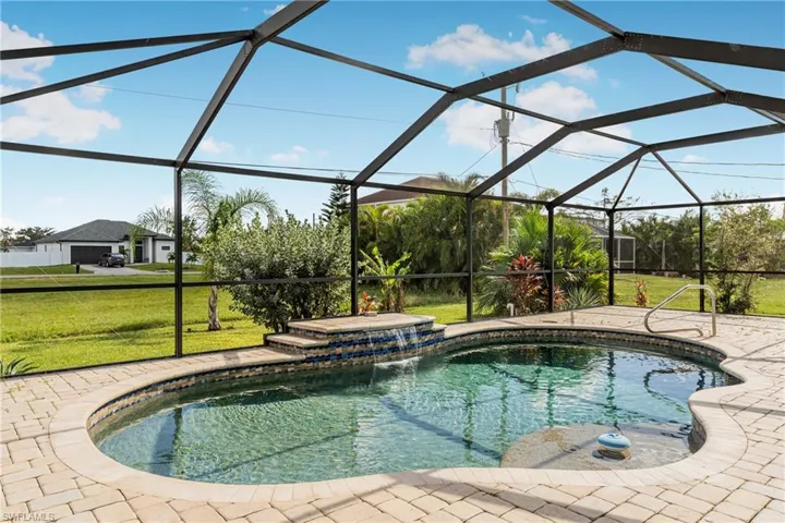 View of swimming pool featuring glass enclosure, a patio area, a yard, and pool water feature