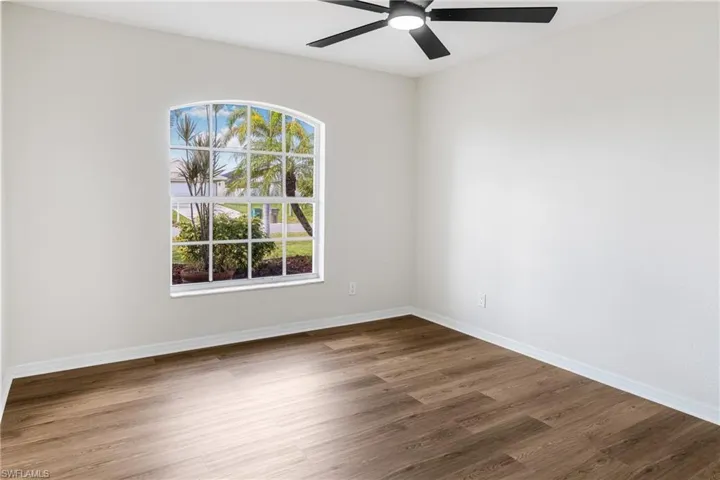 Unfurnished room featuring dark wood-type flooring and ceiling fan