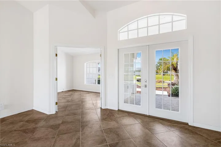 Doorway featuring a towering ceiling, french doors, and dark tile patterned flooring