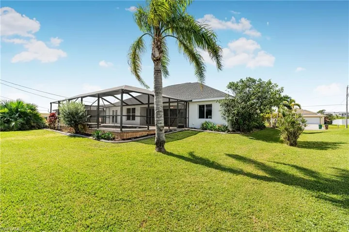 Rear view of house with a yard and glass enclosure