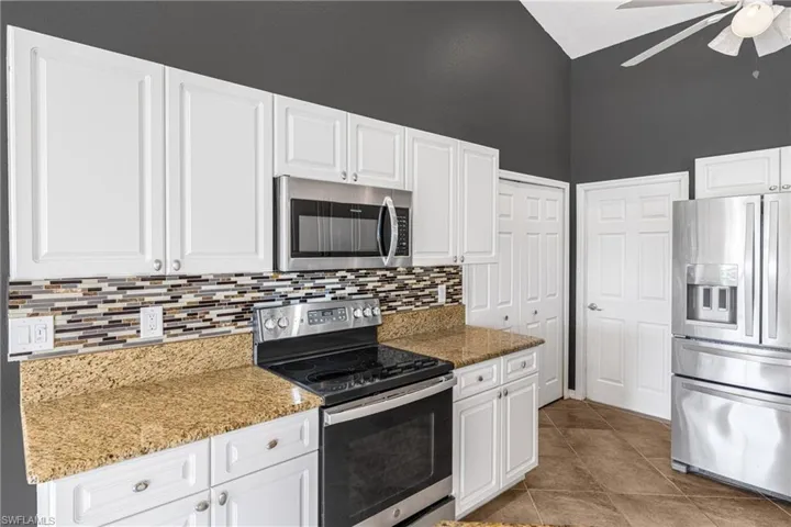 Kitchen featuring white cabinetry, light stone counters, light tile patterned floors, and stainless steel appliances