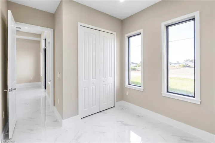Unfurnished bedroom with light marble finish floors and a closet