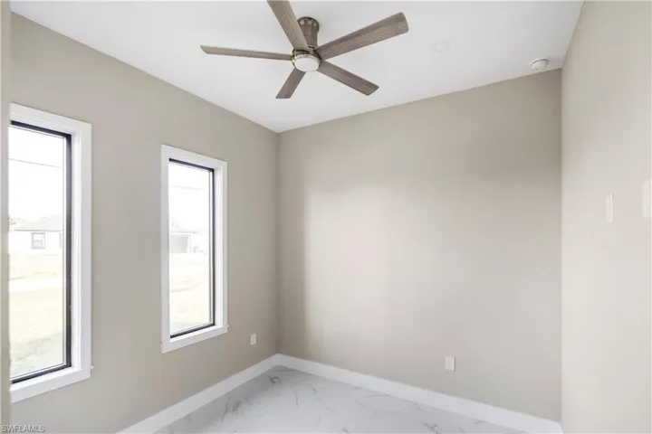 Empty room featuring light marble finish floors and a ceiling fan