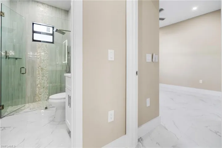 Full bath featuring a marble finish shower, light marble finish floors, and vanity