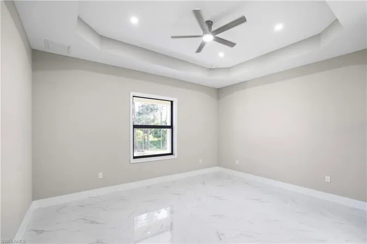 Spare room with a tray ceiling, light marble finish flooring, ceiling fan, and recessed lighting