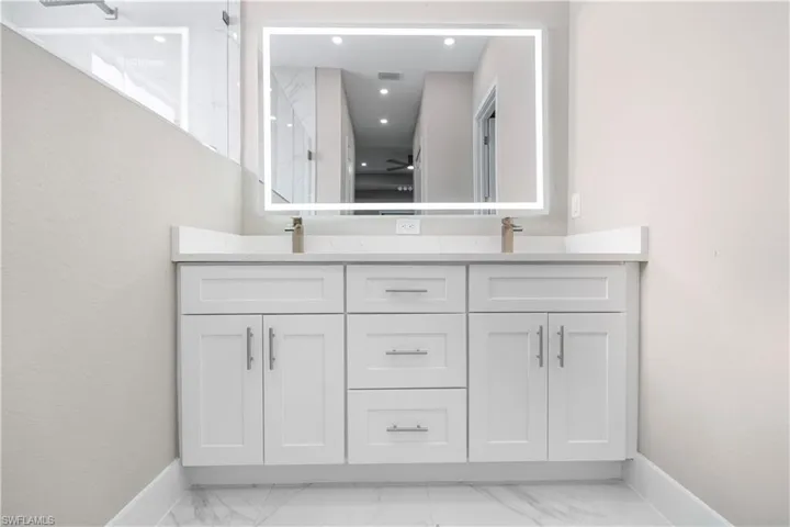 Bathroom featuring double vanity, recessed lighting, and light marble finish flooring