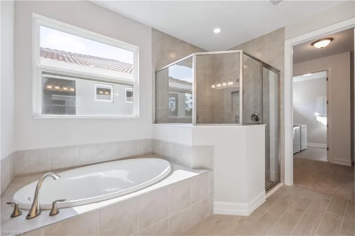 Bathroom featuring washing machine and dryer, hardwood / wood-style floors, and shower with separate bathtub