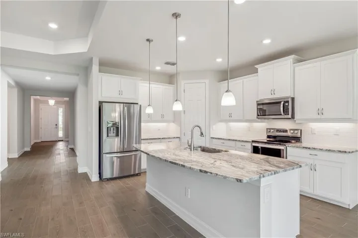 Kitchen with white cabinets, sink, a center island with sink, hardwood / wood-style flooring, and stainless steel appliances