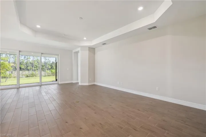 Empty room featuring a tray ceiling and hardwood / wood-style floors
