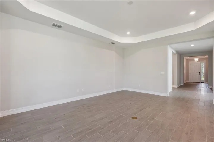 Empty room with light hardwood / wood-style flooring and a tray ceiling