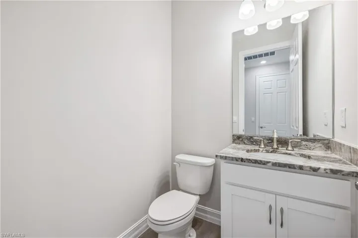 Bathroom featuring wood-type flooring, vanity, and toilet