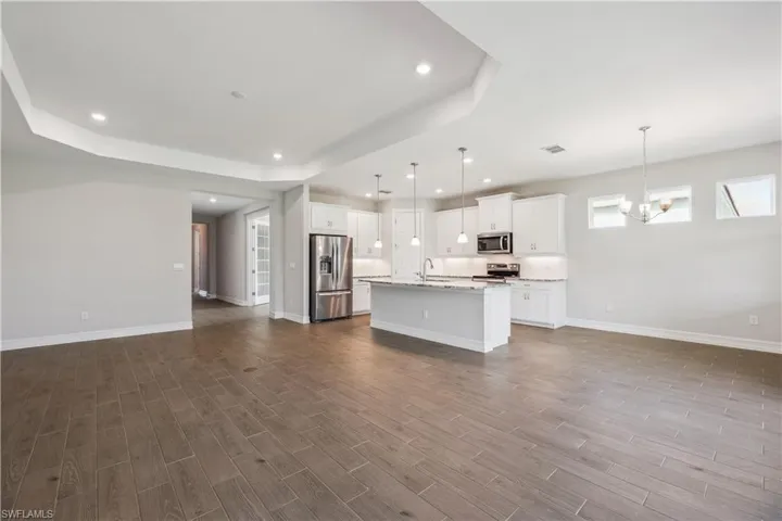 Kitchen featuring decorative light fixtures, hardwood / wood-style flooring, appliances with stainless steel finishes, and white cabinets