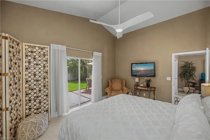 Vaulted ceiling with a contemporary ceiling fan, sliding glass door to exterior patio, wood-finish flooring, and a decorative room divider screen