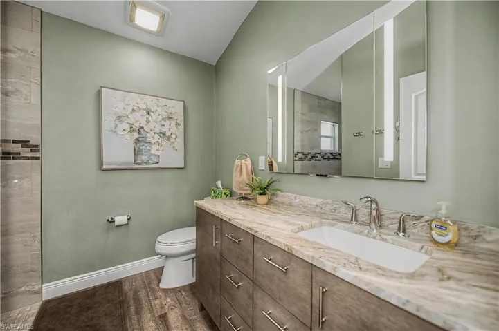 Bathroom featuring a spacious vanity with integrated sink, stone countertop, and wood-finish cabinetry