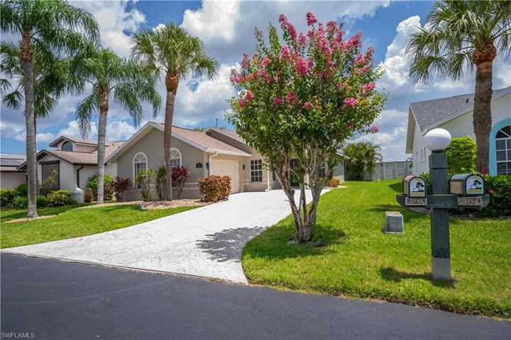 Stucco exterior with an attached garage, arched windows, and a concrete driveway