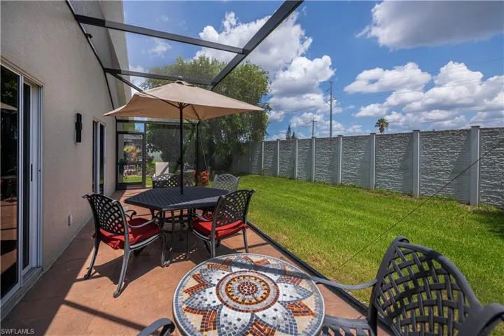 Screened patio featuring a textured concrete floor, stucco exterior, and a manicured lawn