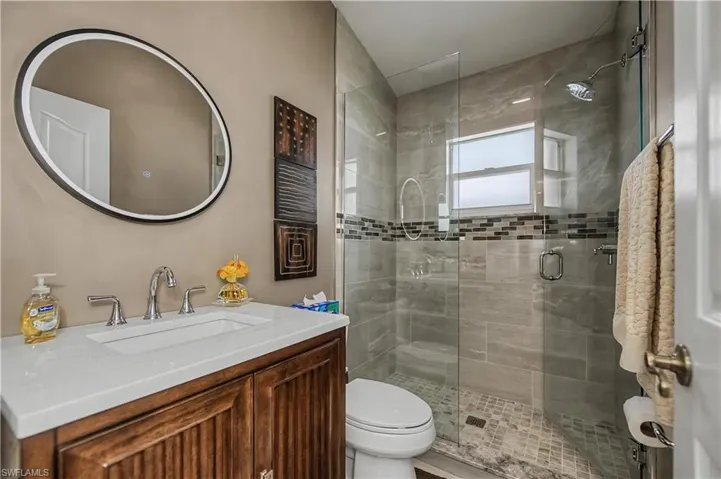 Bathroom featuring a glass-enclosed shower with tile surround and mosaic accent band