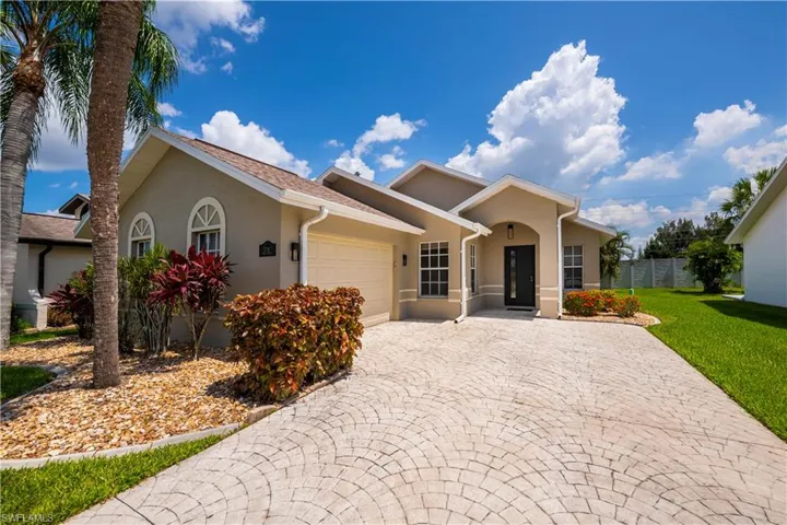 Single-story stucco residence featuring a decorative paver driveway, an arched entry, and a two-car garage