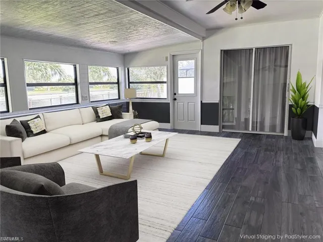 Living room featuring wood finished floors, beamed ceiling, and ceiling fan