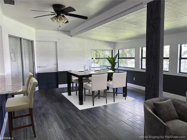 Dining area featuring dark wood-type flooring, beamed ceiling, and a ceiling fan