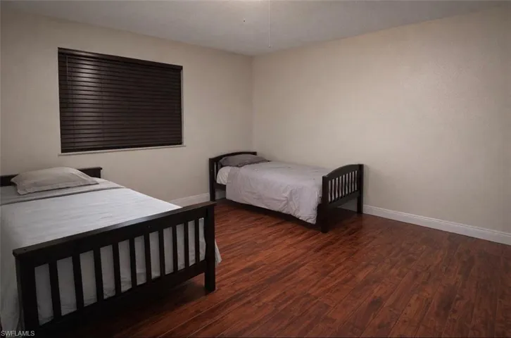 Bedroom featuring dark wood-type flooring and baseboards